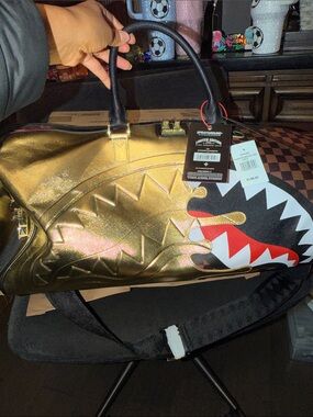 Sprayground Metallic Gold Shark Duffle with Black Handles and Red Accent